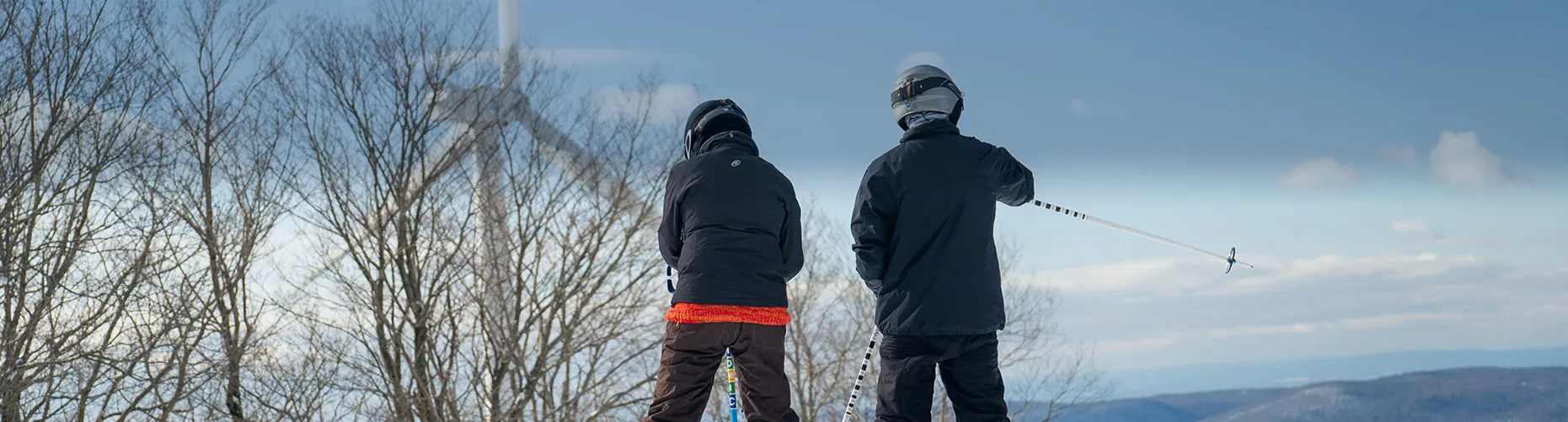 Two skiers with wind turbine in background
